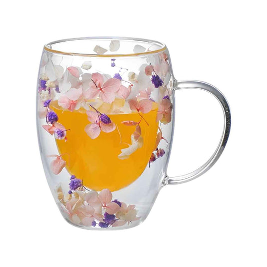 Tasse en verre à double paroi avec des pétales roses, blancs et violets à l'intérieur et une anse, idéale pour une soirée café ou thé.